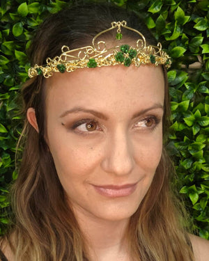 Model wearing Royal Rose Crown gold floral headpiece with green rose accents and crystal drop, front view.