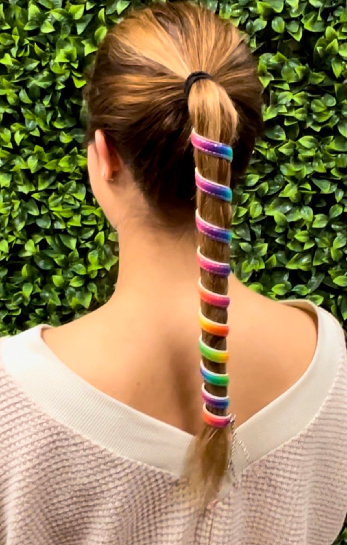 Model wearing a 12 inch rainbow leather ponytail wrap in long blonde hair with colorful adjustable spiral leather hair wrap.