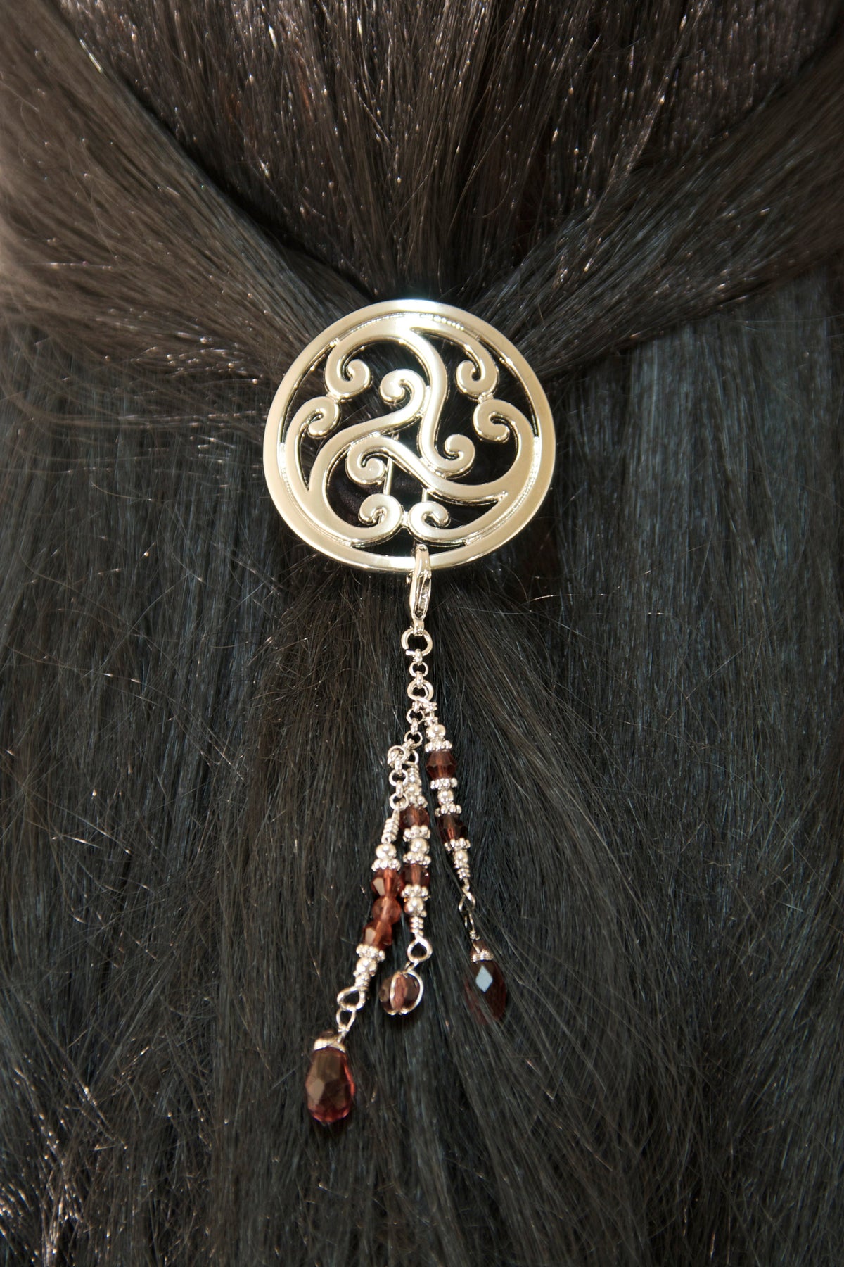 Silver Celtic hair hook with dangling bead charms worn in a model's ponytail