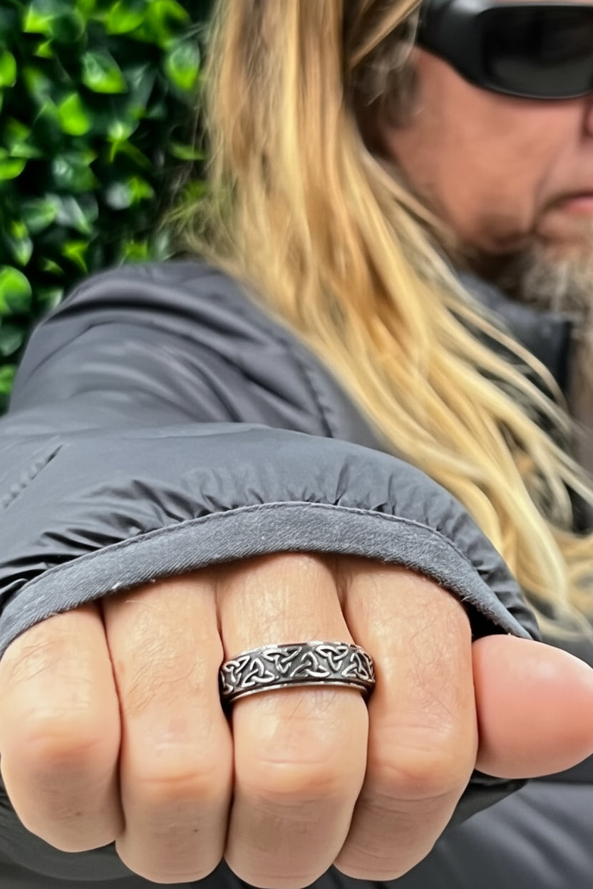 hand wearing black and silver celtic knot band ring