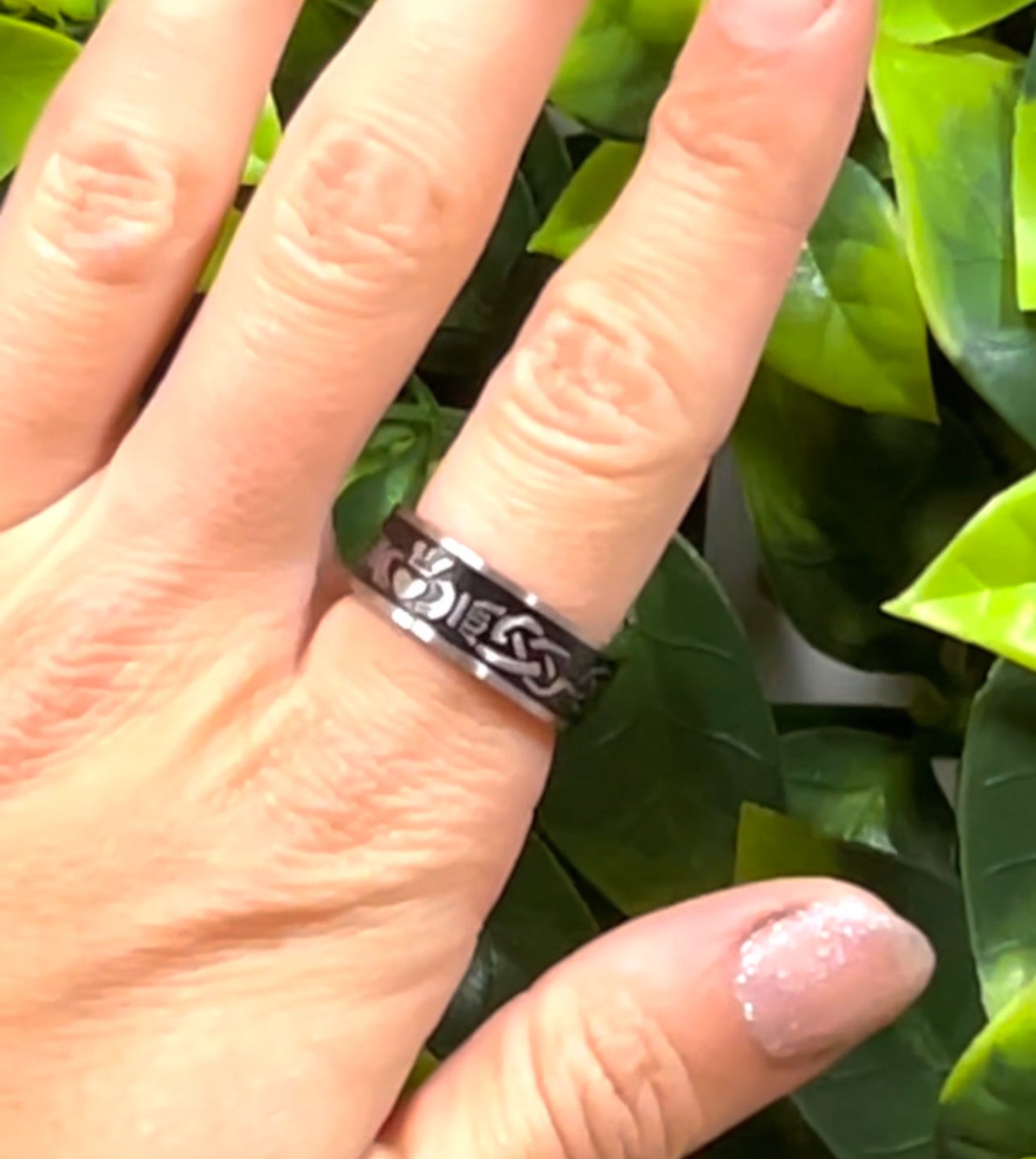 hand wearing stainless steel claddagh band ring with celtic pattern black inlay