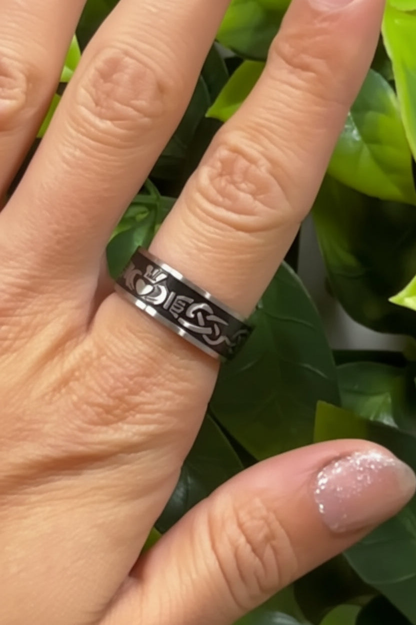 hand wearing stainless steel claddagh band ring with celtic pattern black inlay
