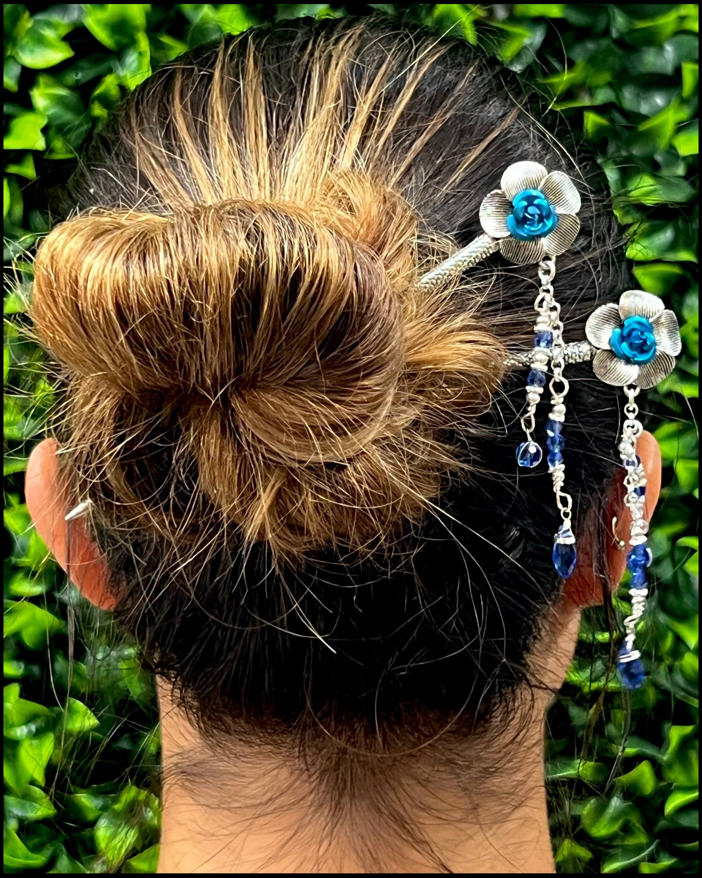 Model wearing Flower & Bead Hair Sticks with blue floral accents and dangling beads in a bun hairstyle.