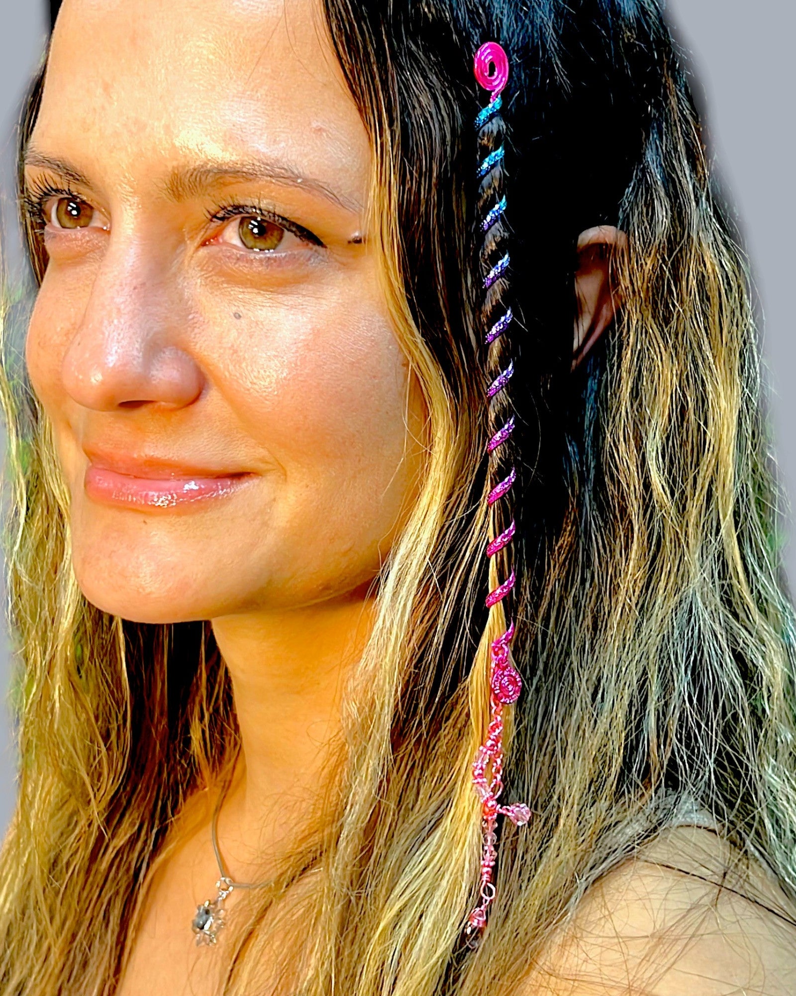 6 inch pink hair twister in long wavy blonde hair, metal spiral hair accessory styled in braid with dangling charm, side profile