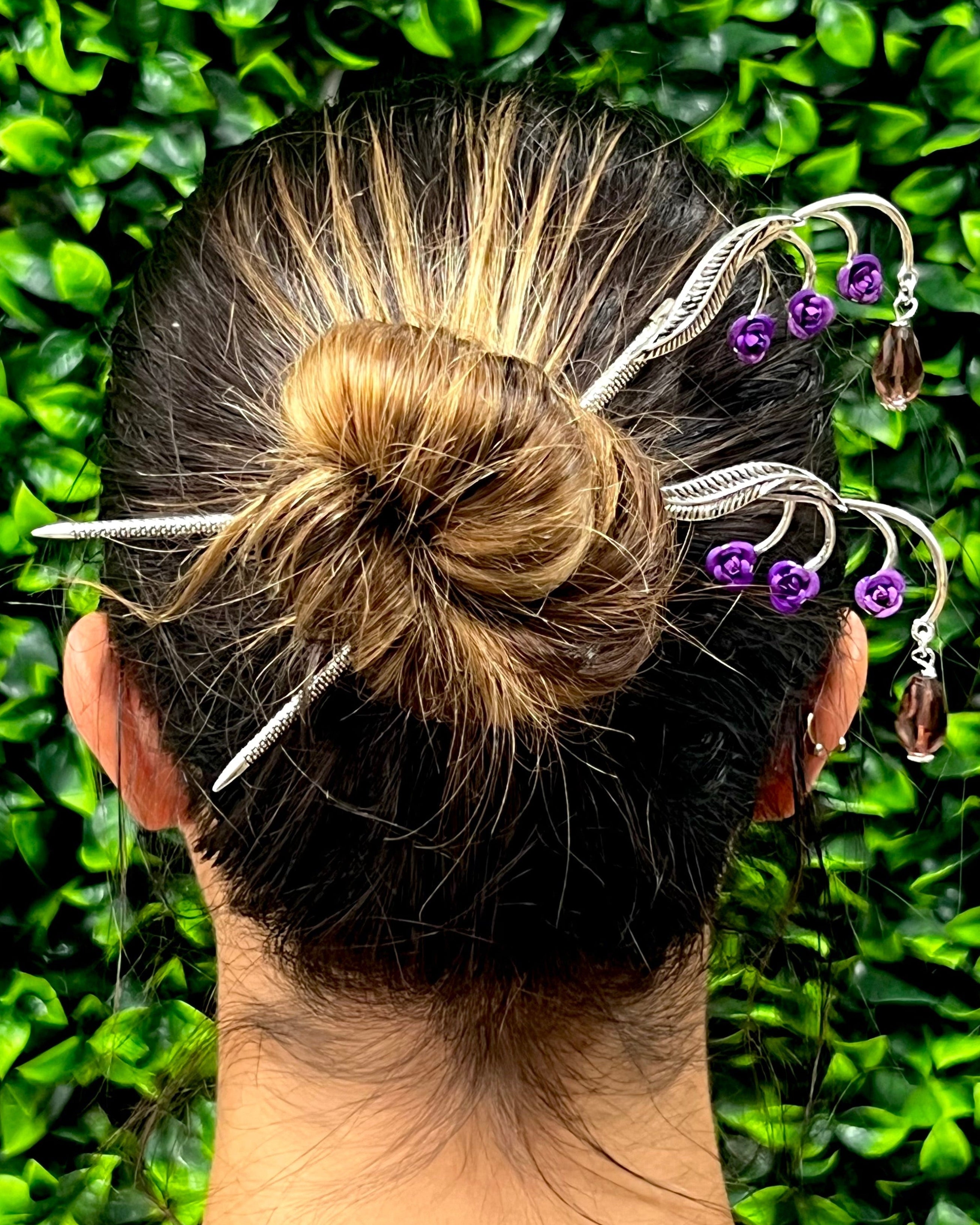 Leafy Flower Gems Hair Sticks worn in a bun hairstyle, side view showing silver leafy branches with purple flower accents and dangling crystal charms.