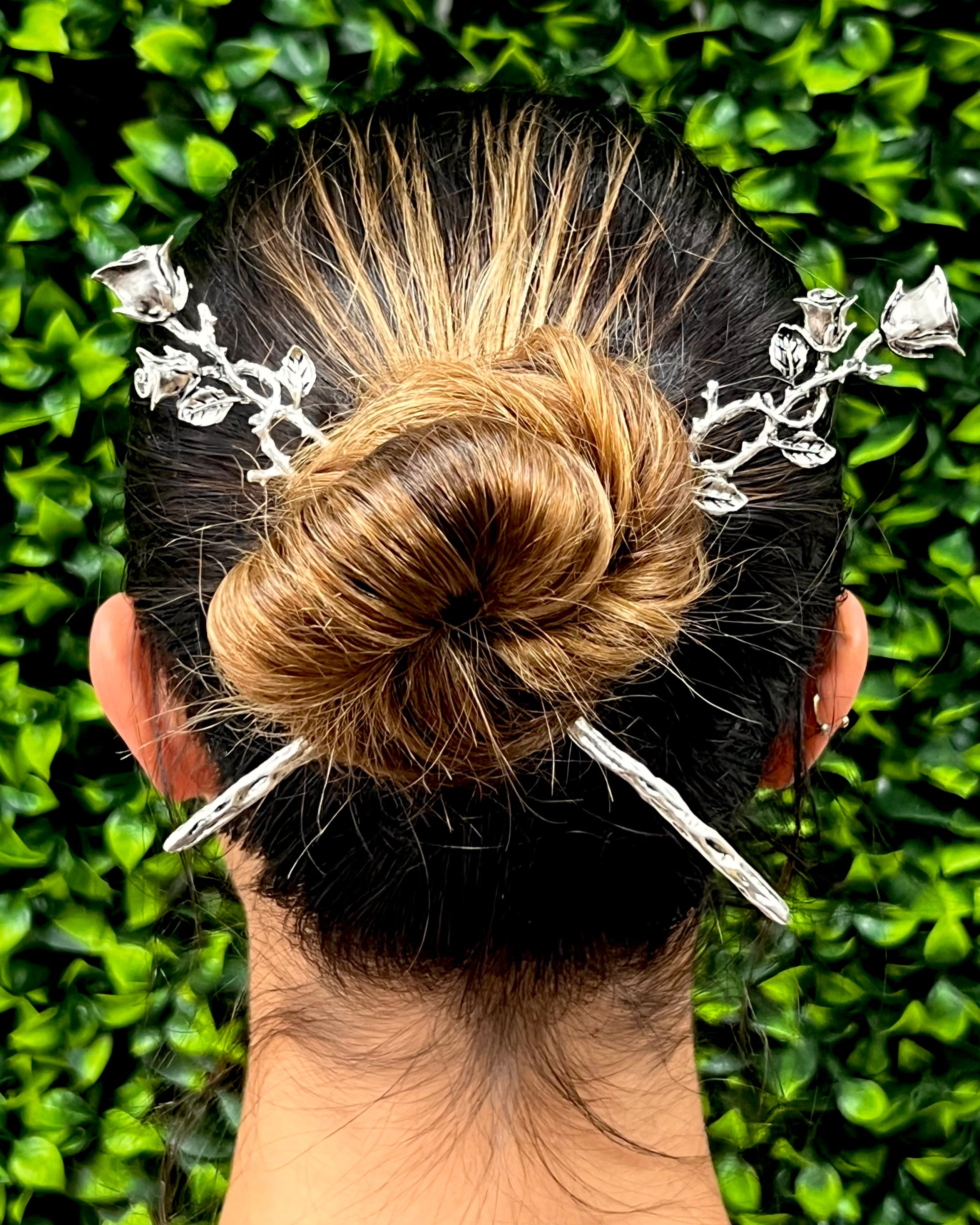 Model wearing silver Elegant Rose Vine Hair Sticks with floral rose vine design securing a bun hairstyle.