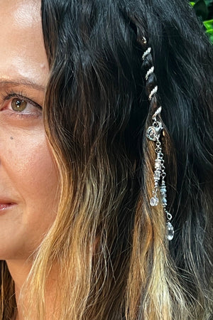 Woman wearing a 2-inch silver Hair Twister spiral hair wrap with crystal bead charm, securing a small hair section as decorative hair jewelry, side view.