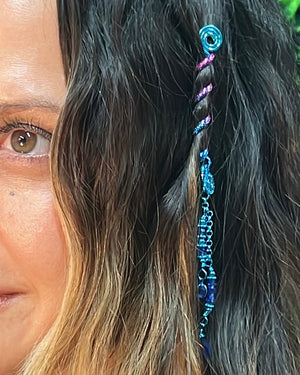 Close-up of a 2-inch blue Mini Hair Twister spiral hair accessory with blue bead charm, worn in long wavy hair.