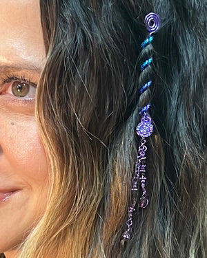 Close-up of a 2-inch purple Hair Twister spiral hair accessory with dangling purple bead charm, worn in long wavy hair.