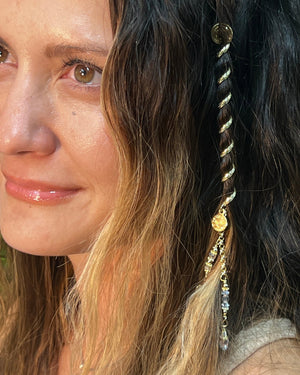 Woman wearing a 4-inch gold Hair Twister spiral hair wrap with crystal charm accent, securing a section of hair as decorative hair jewelry, side view.
