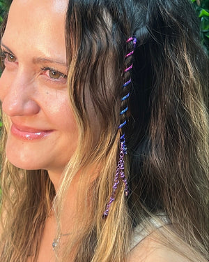Close-up of a 4-inch rainbow Hair Twister spiral hair accessory with purple bead charm, worn in long wavy hair.
