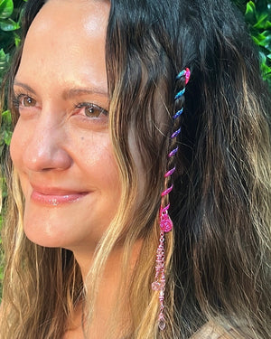 Close-up of a 4-inch rainbow Hair Twister spiral hair accessory with pink bead charm, worn in long wavy hair.