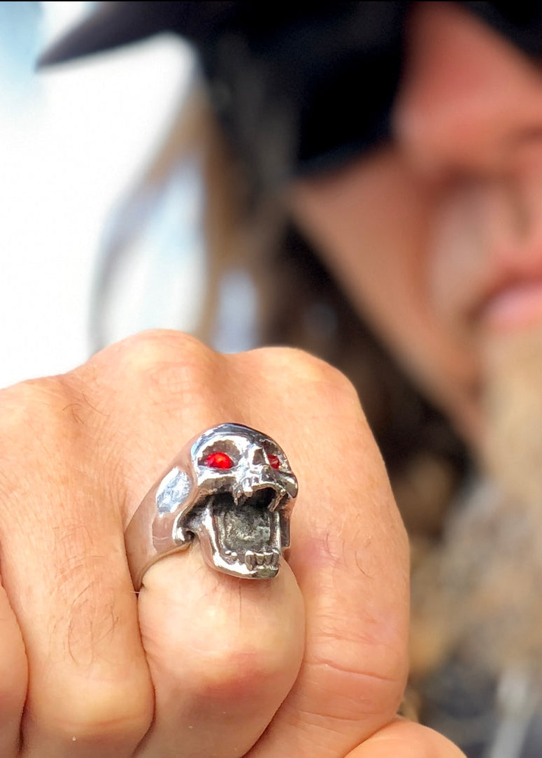Man wearing a skull beer bottle opener  ring with a blurred background