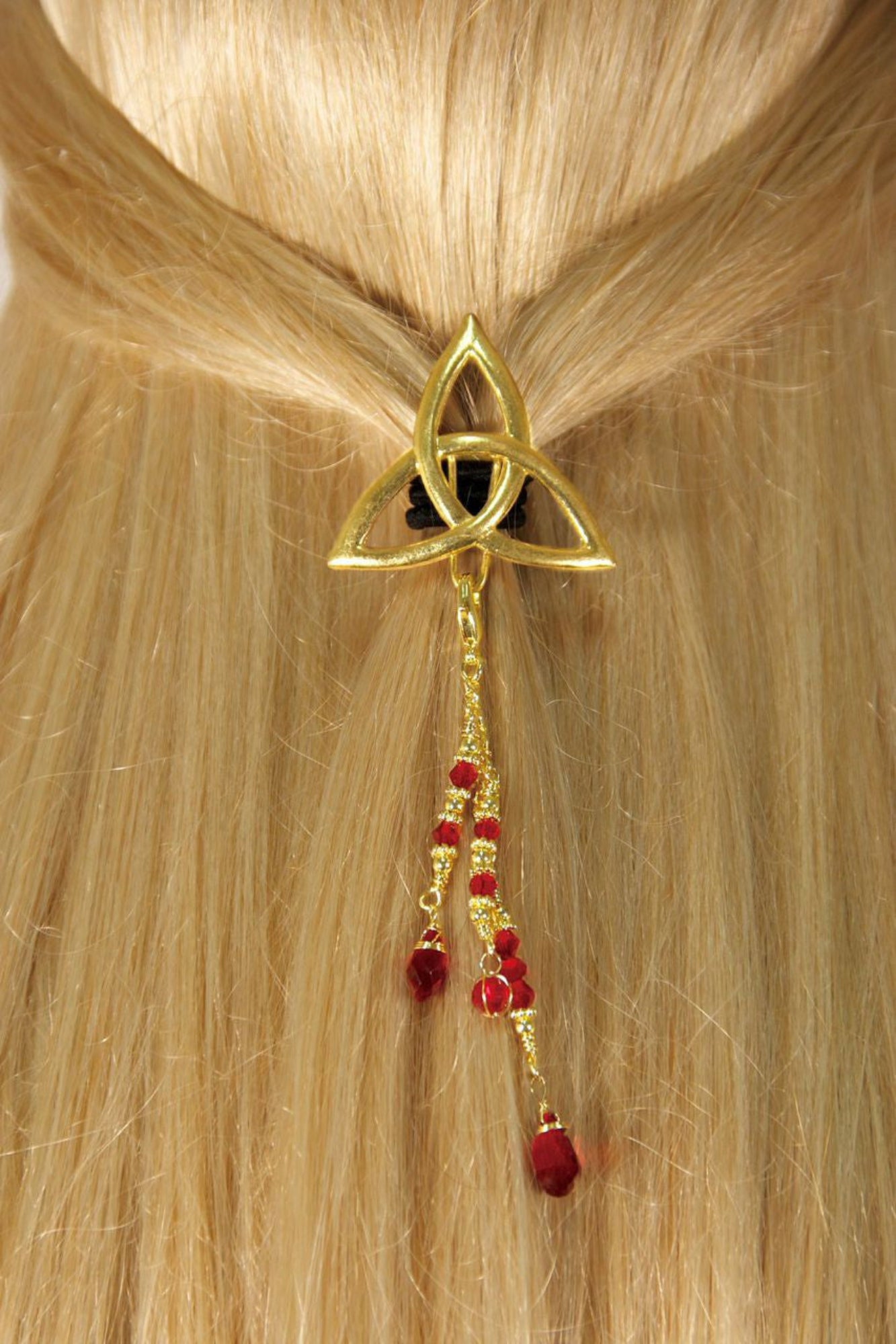 Gold Celtic triquetra hair hook with dangling red bead charms worn in ponytail, back view