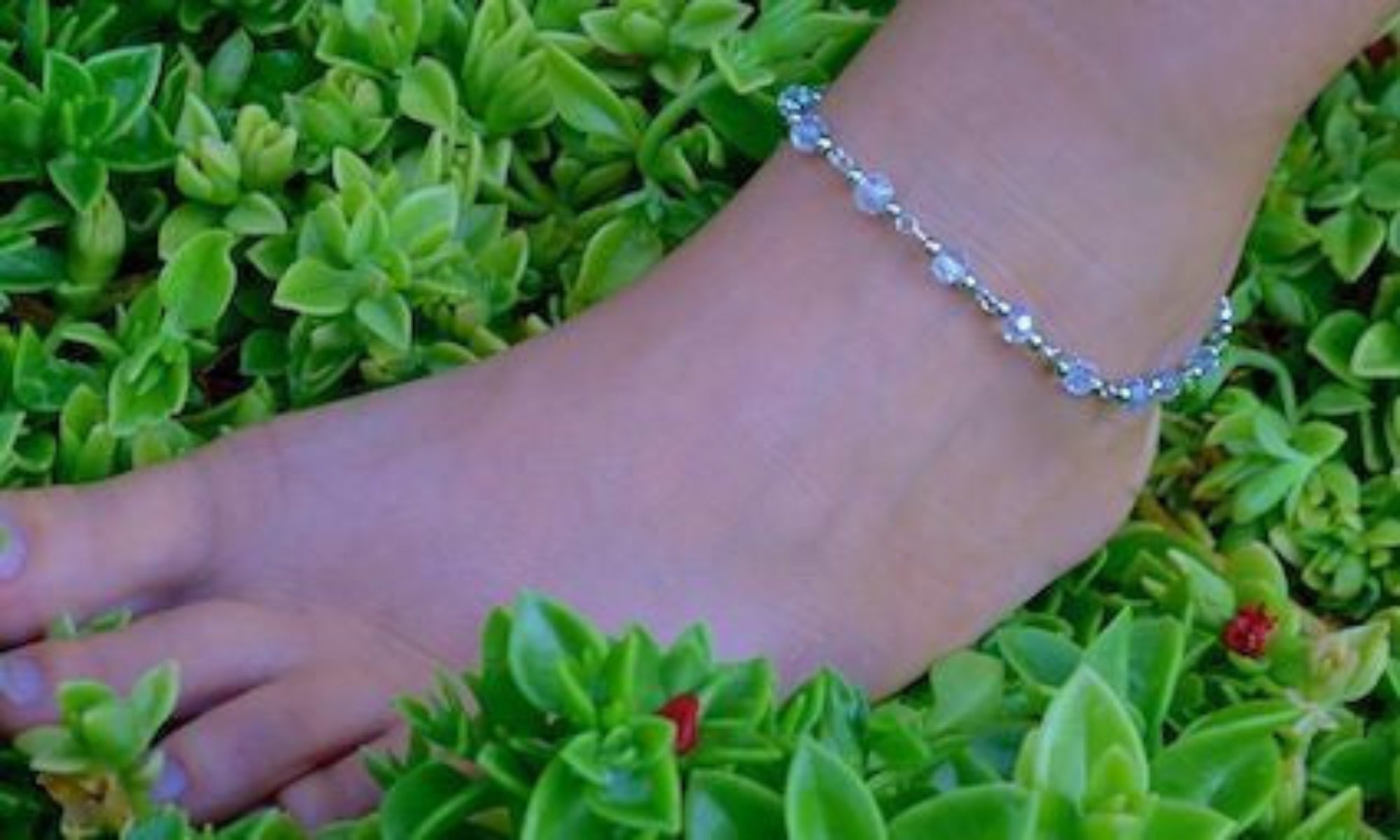 Silver chain anklet with pink faceted beads worn on ankle, outdoor garden setting
