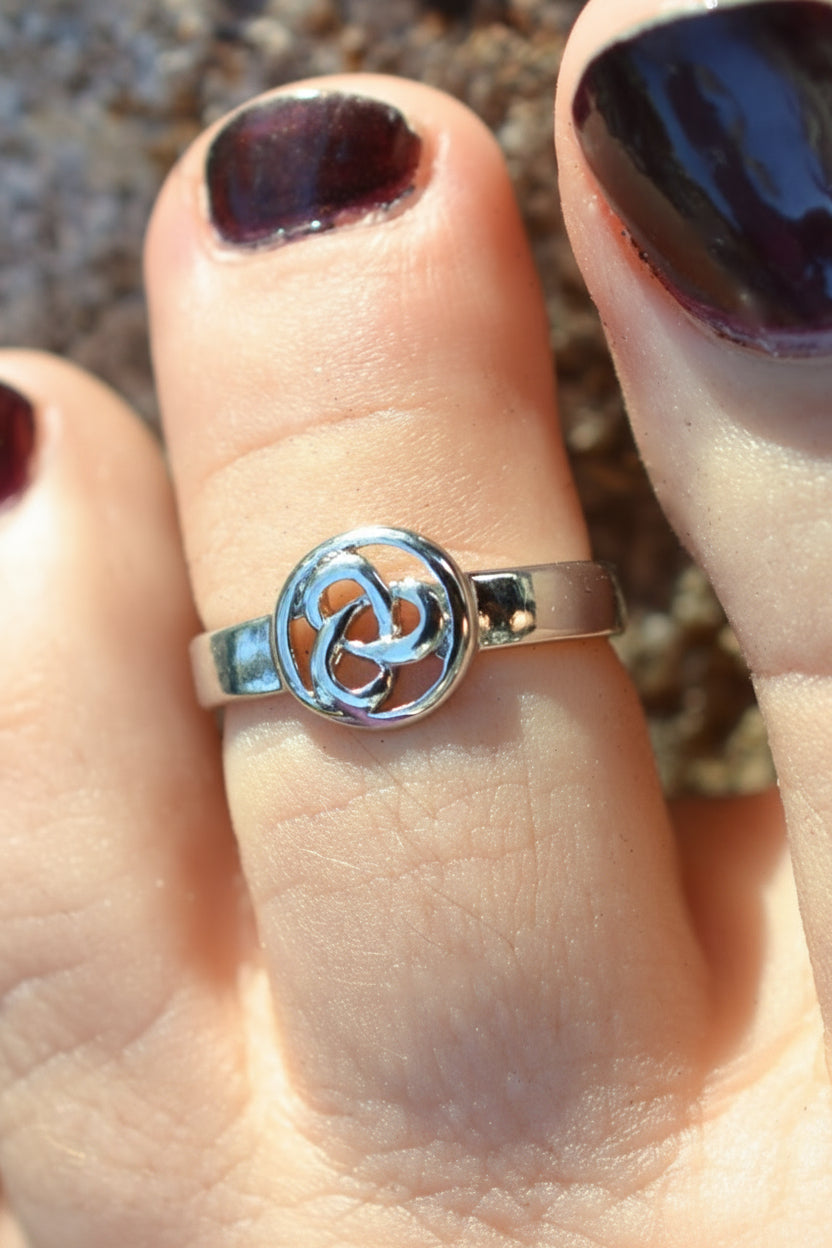 Silver Celtic triquetra toe ring worn on toe beach sand background