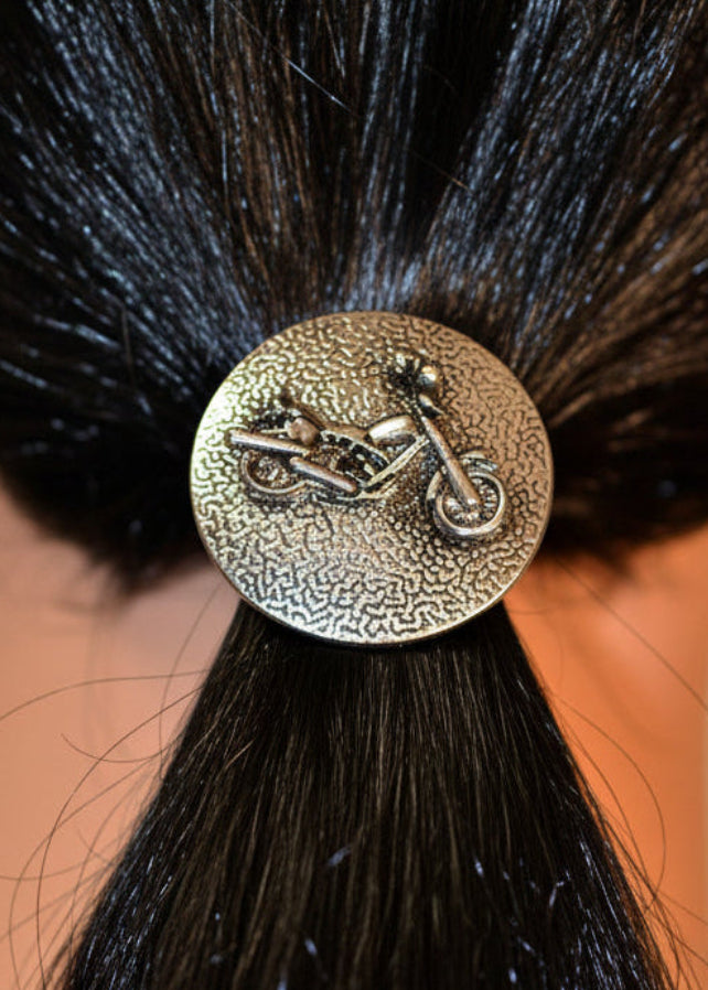 Silver motorcycle hair hook with textured round base, worn in ponytail, back view