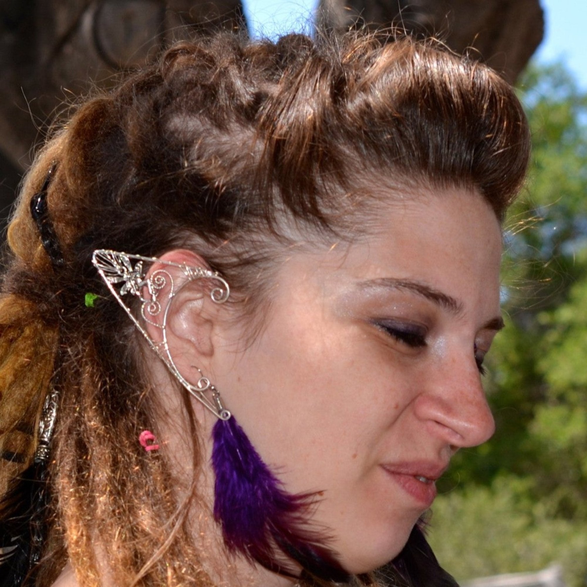 Model wearing silver fairy elf ear cuff, wire wrap non-piercing ear jewelry, side view outdoors

