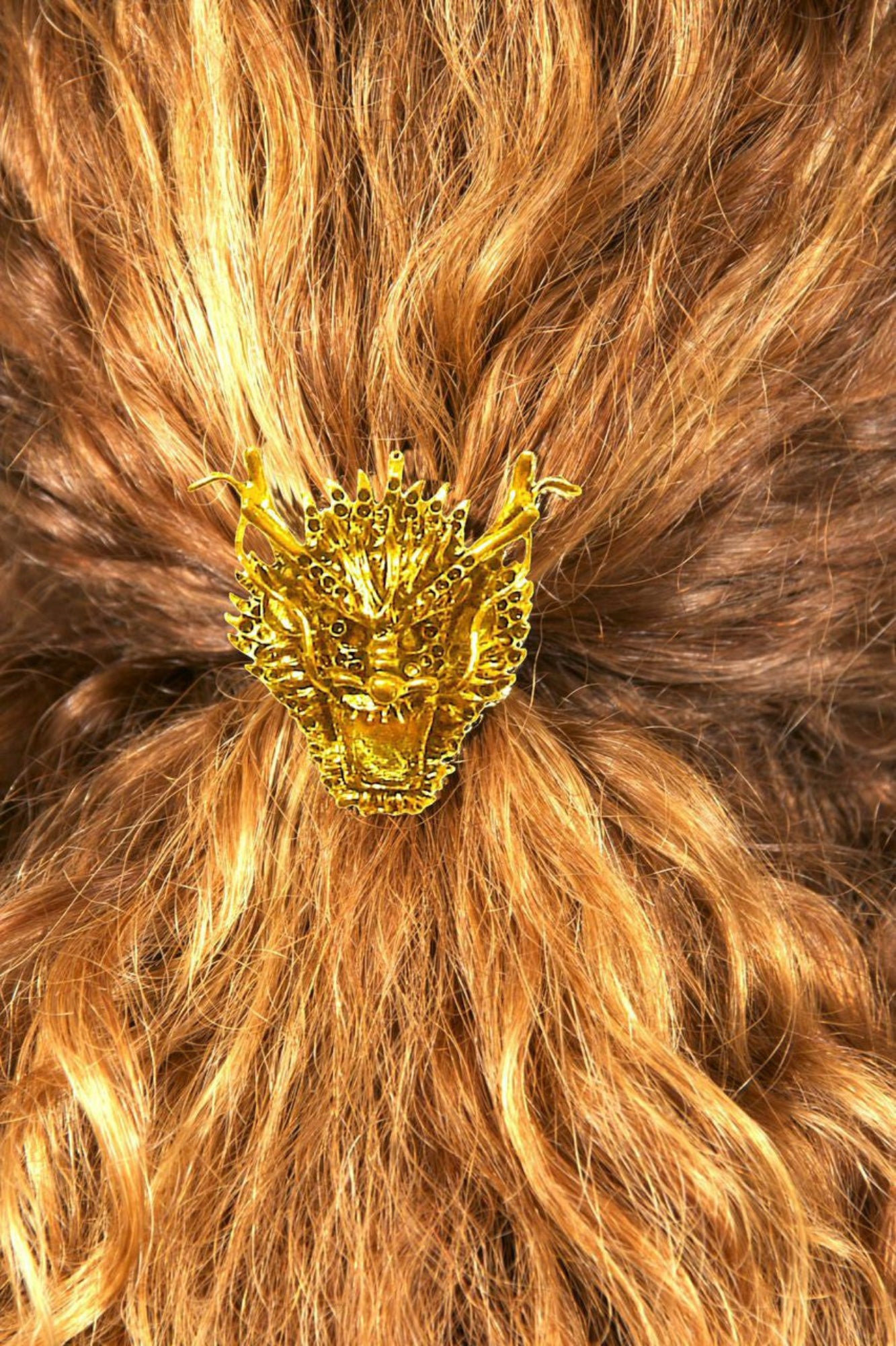 Gold dragon hair hook ponytail holder worn in curly red hair, back view