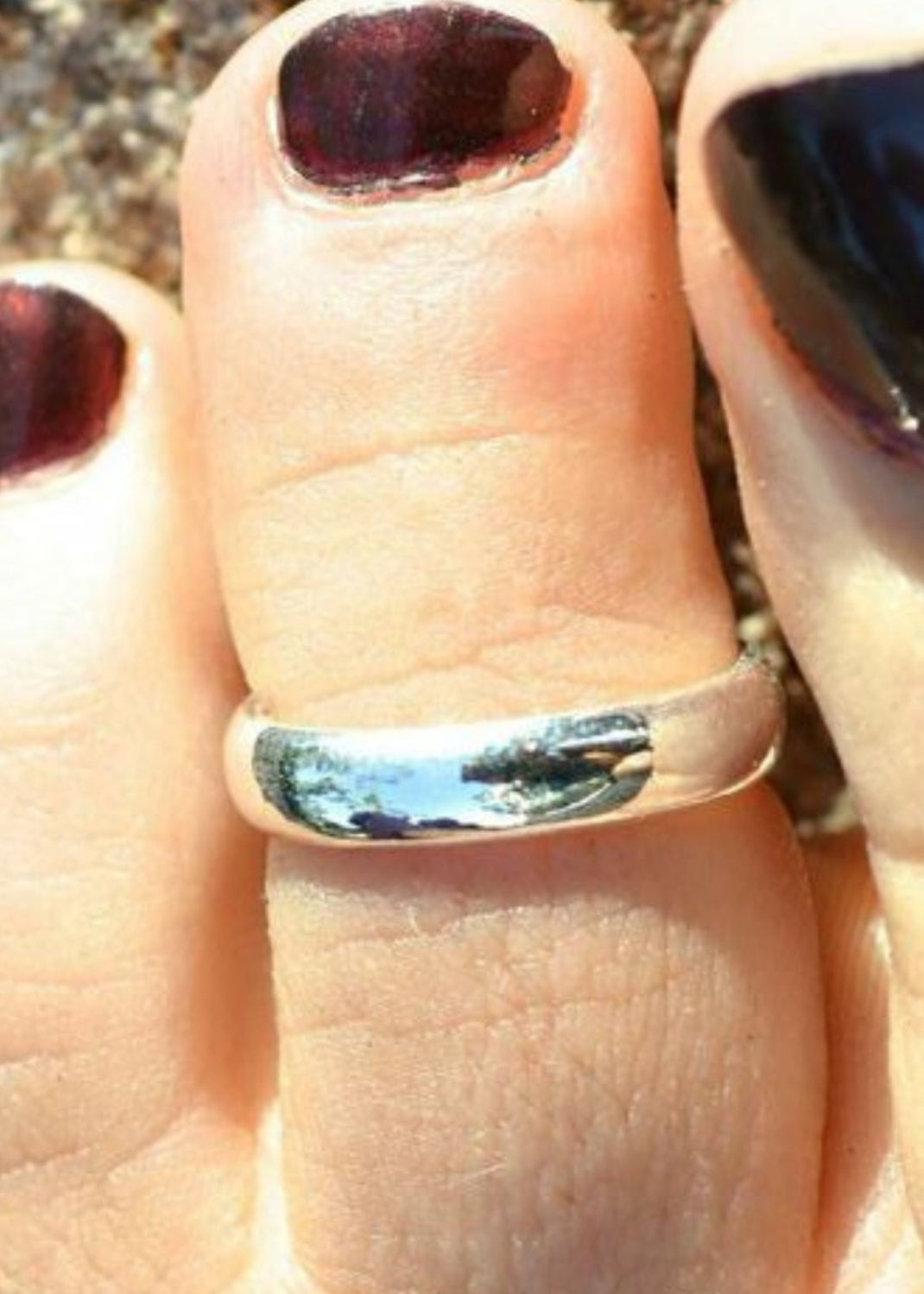 Adjustable silver plain band toe ring worn on foot, close-up view