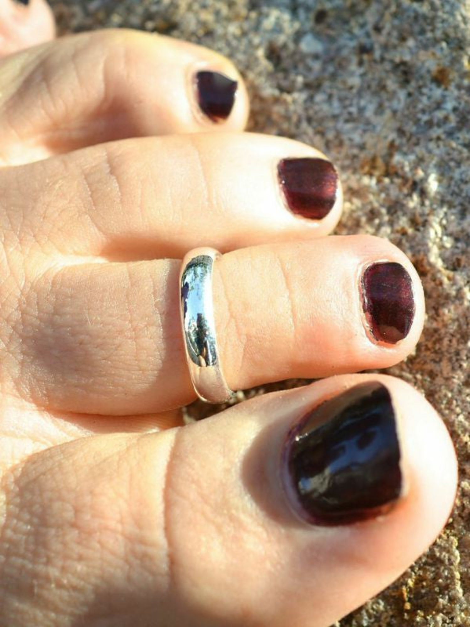 Adjustable silver plain band toe ring worn on foot, close-up view