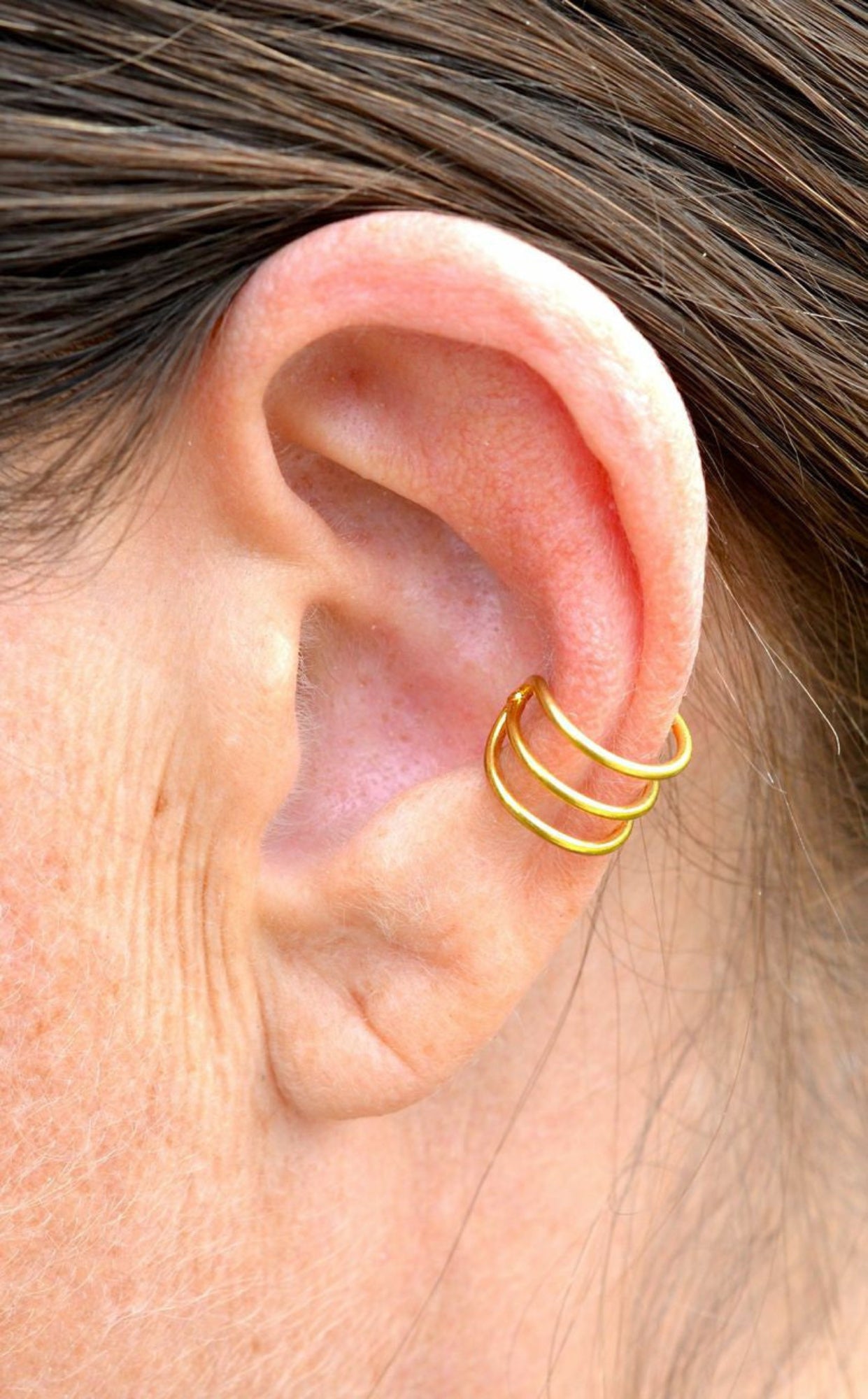Model wearing gold triple strand non-piercing ear cuff on outer ear