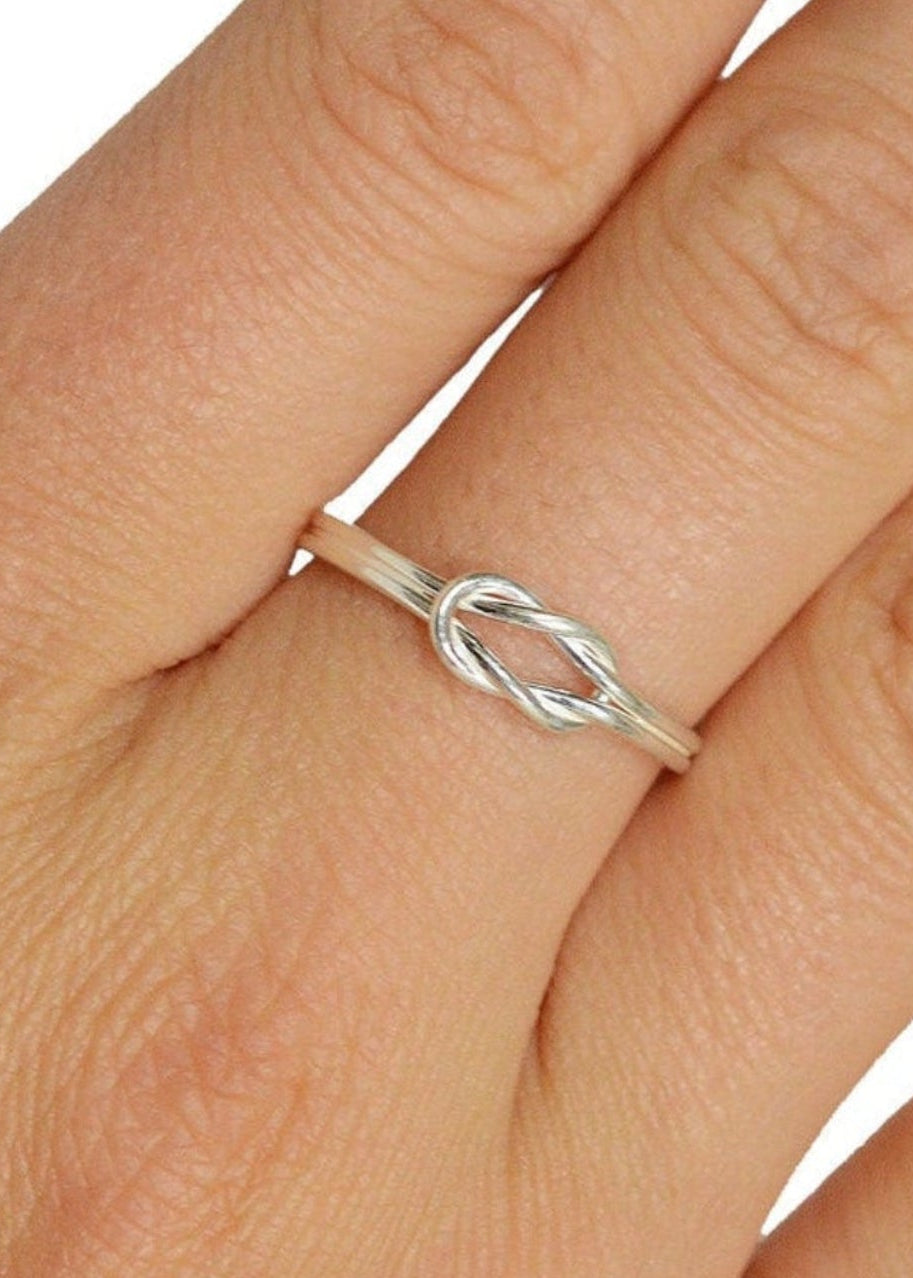 Model wearing Heracles knot sterling silver knot ring on finger, intertwined band design