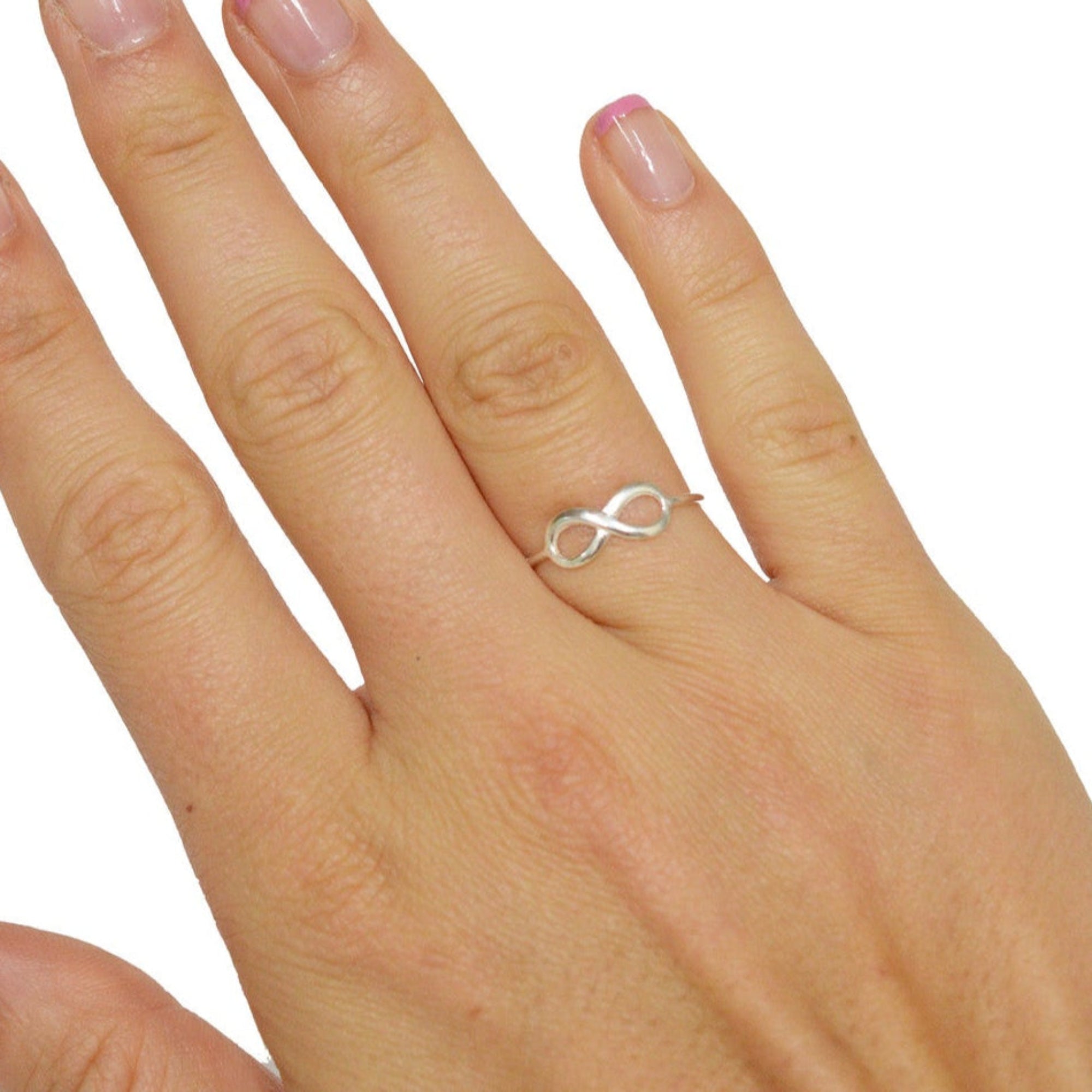 Model wearing infinity thin band ring in sterling silver, minimalist infinity symbol design, front view on hand
