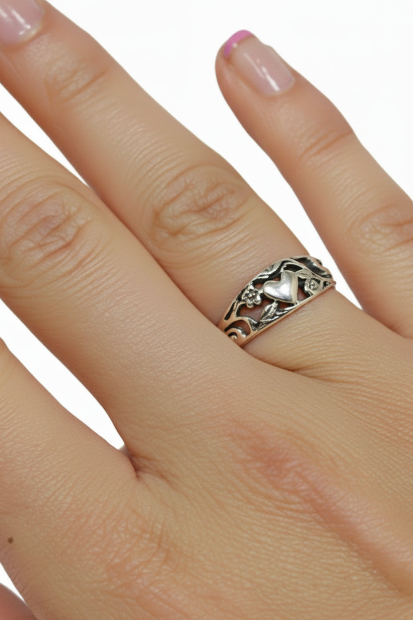 Hand wearing sterling silver heart and flower band ring