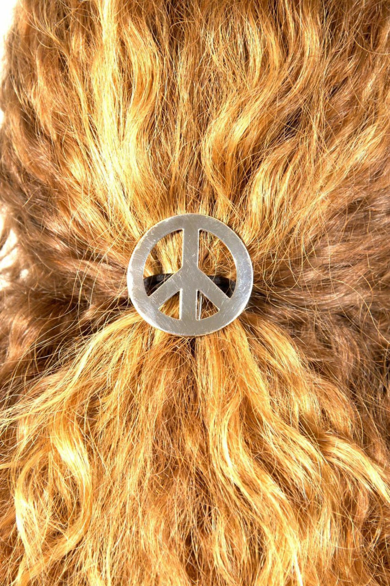 Silver peace sign hair hook securing ponytail, back view