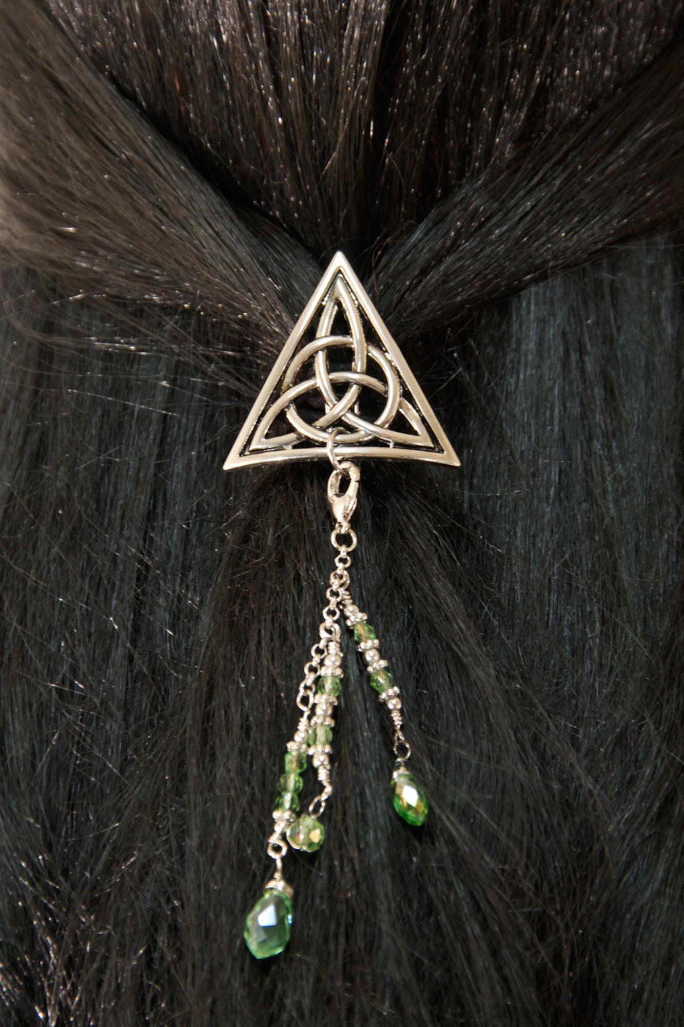 Silver Celtic triangle hair hook with green bead charms worn in dark hair