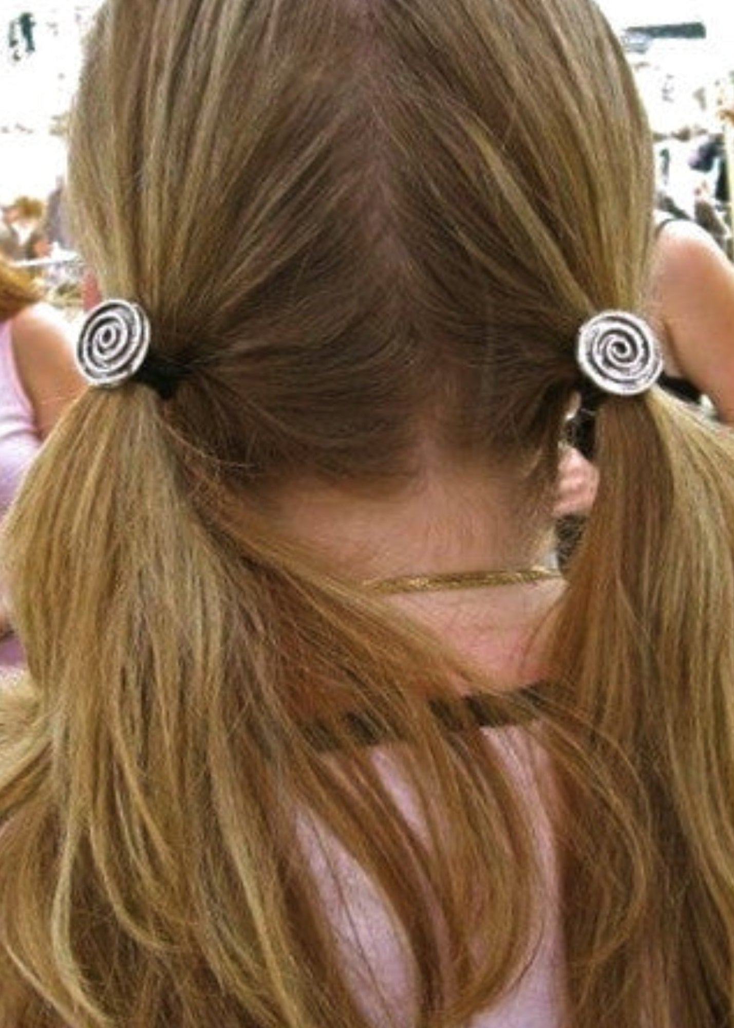 Silver spiral hair hooks securing two low ponytails, rear view