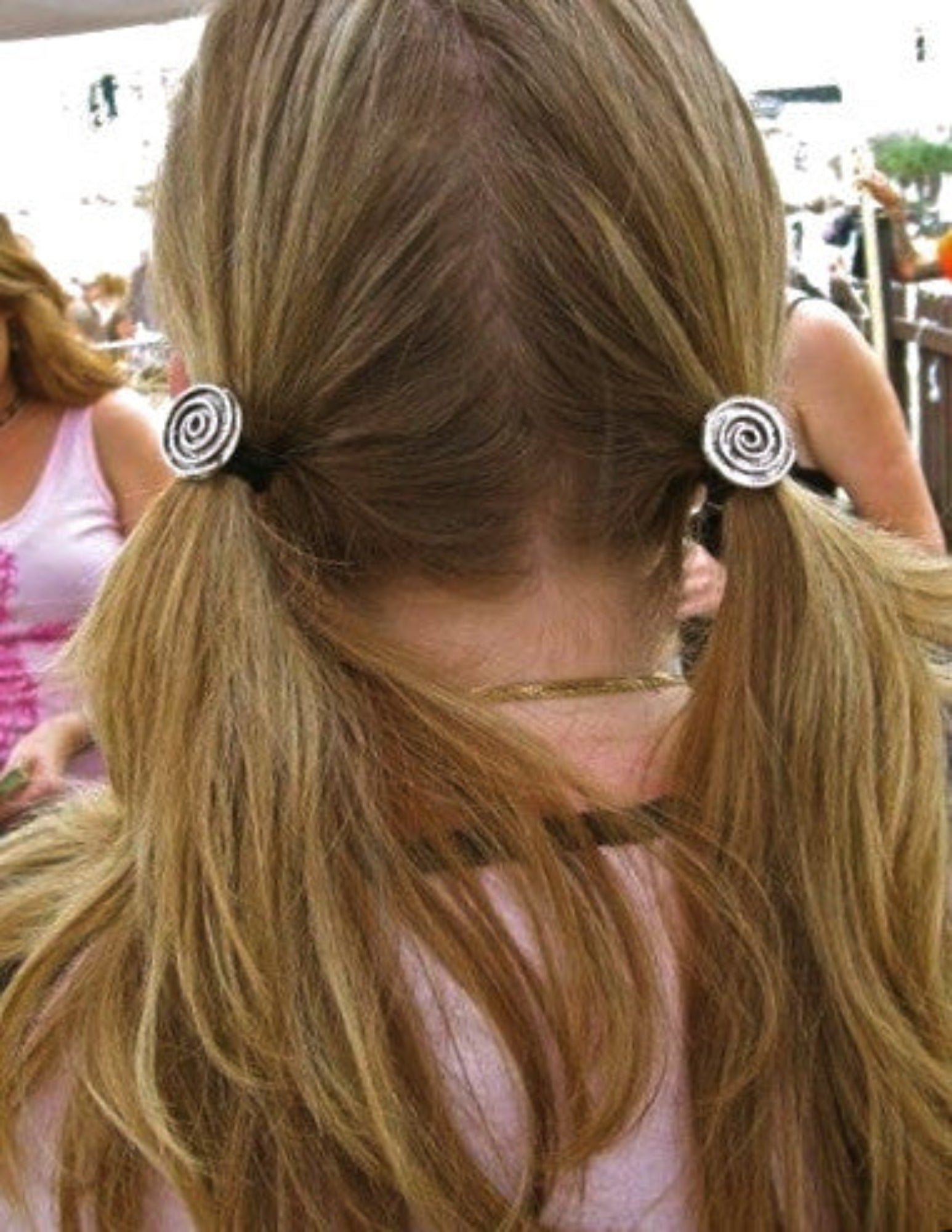 Silver spiral hair hooks securing two low ponytails, rear view
