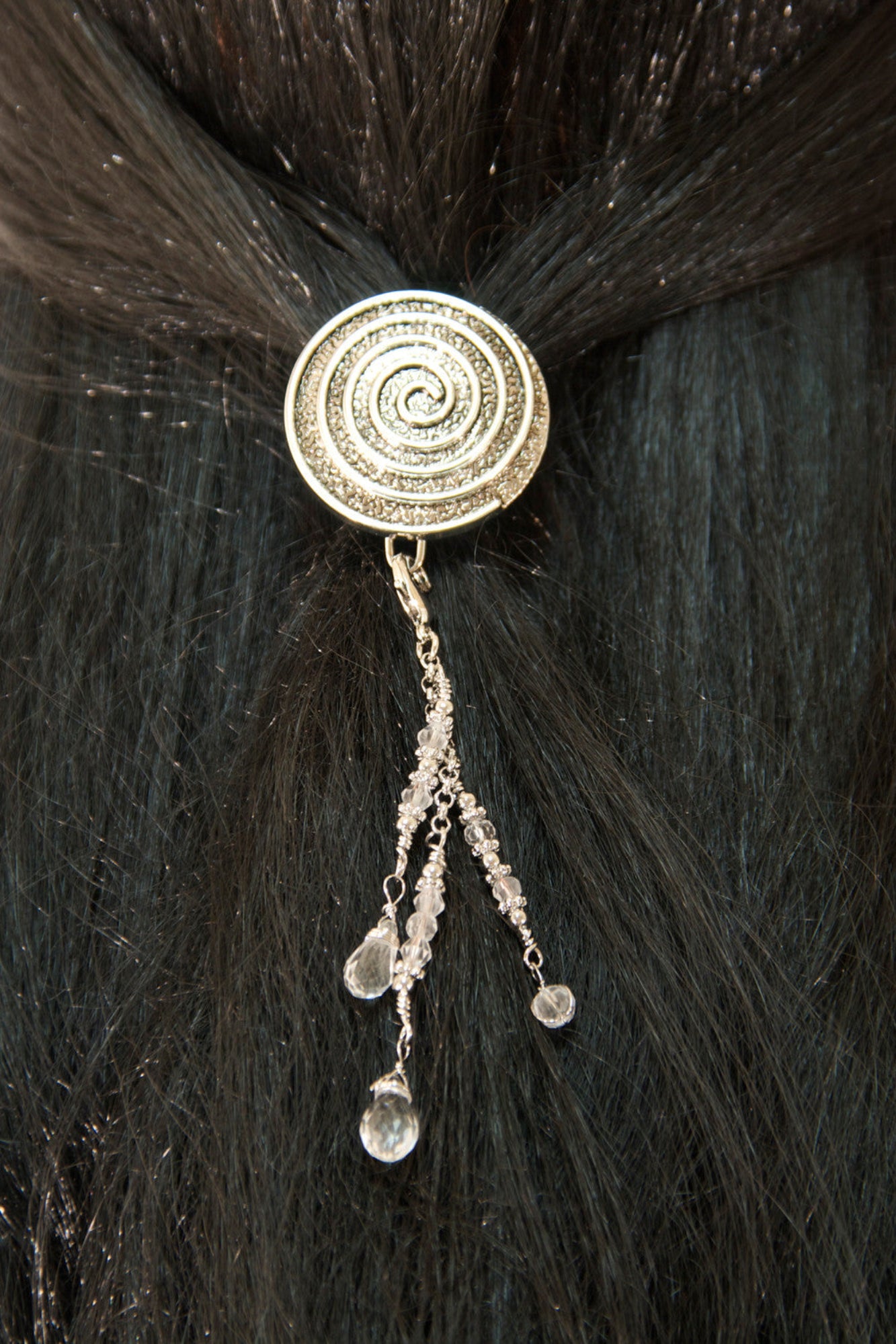 Silver spiral hair hook with dangling bead charms worn in dark hair