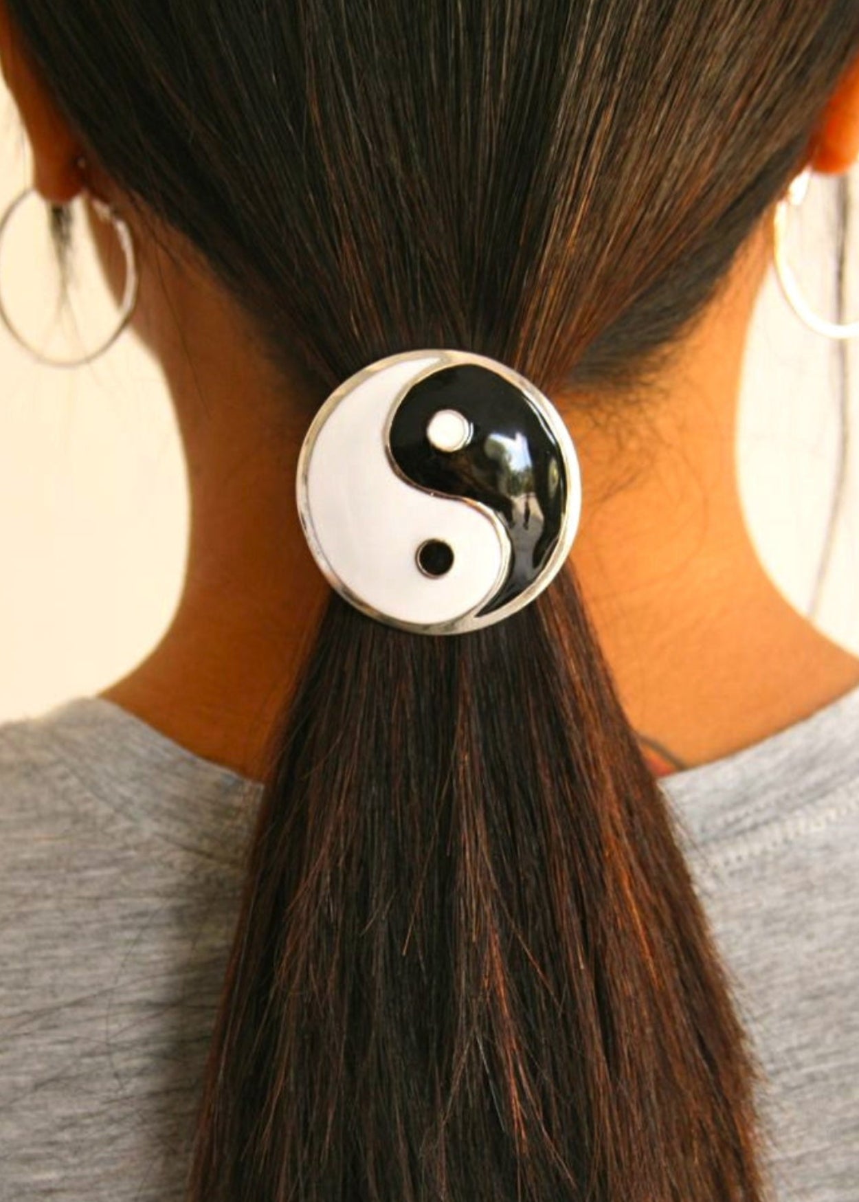 Silver yin yang hair hook securing ponytail, back view