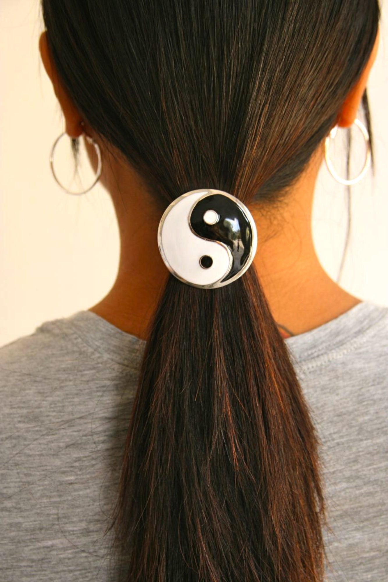 Silver yin yang hair hook securing ponytail, back view