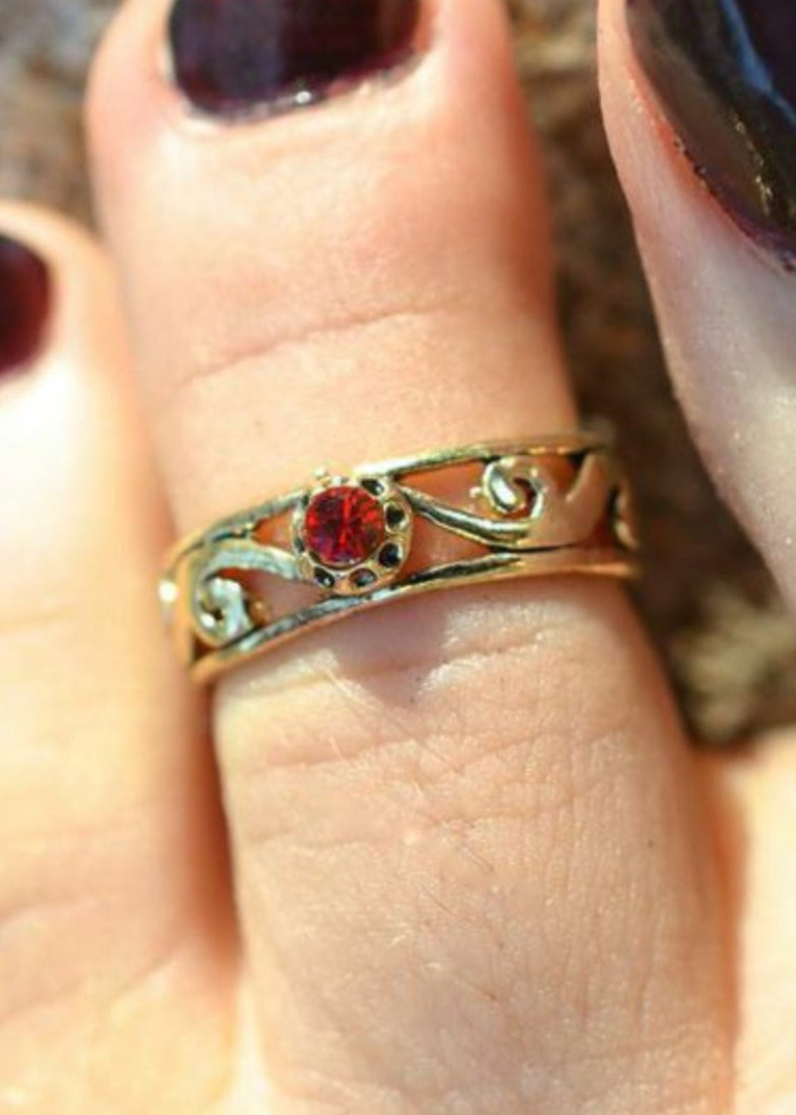 Model wearing spiral band toe ring with gold overlay and red stone
