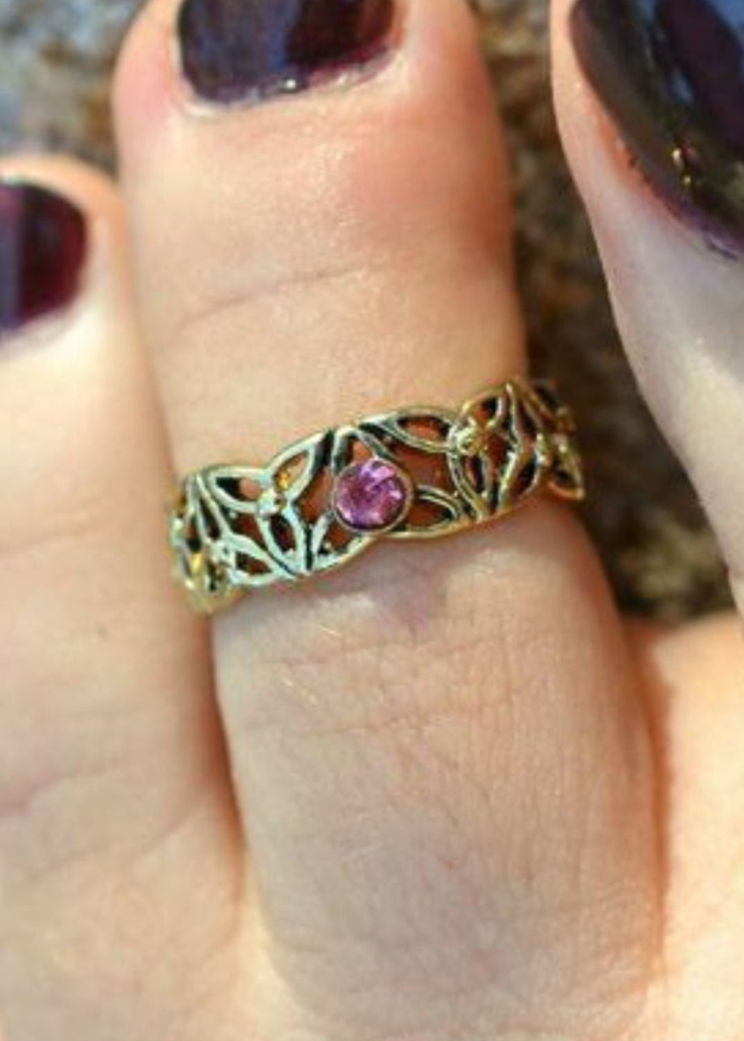Model wearing eternity knot toe ring with gold overlay and purple stone