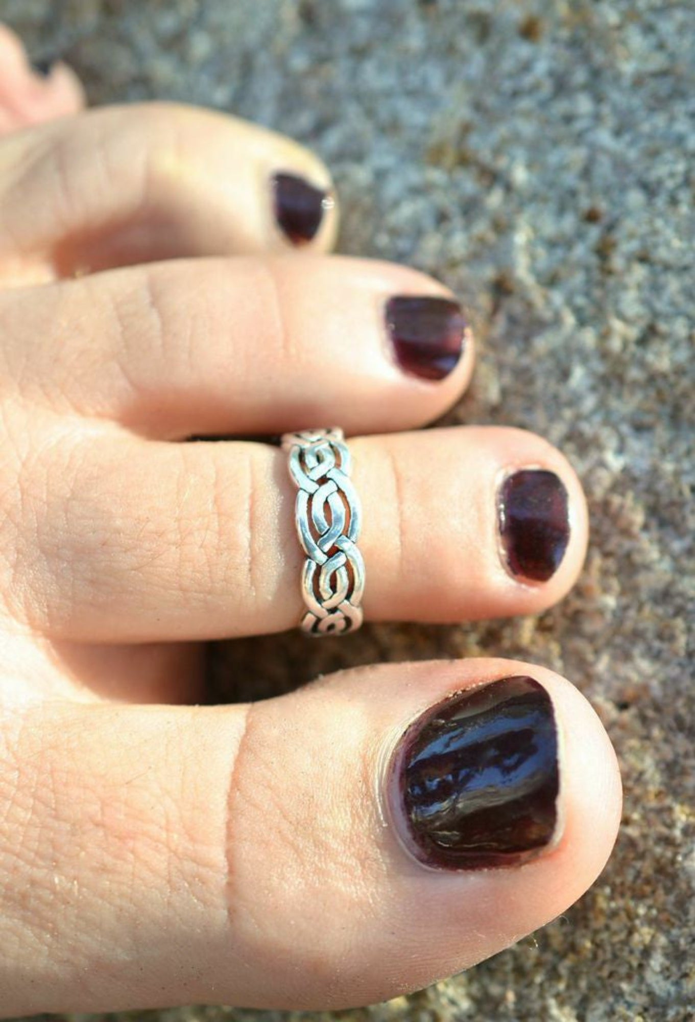 silver celtic knot toe ring on toe with dark nail polish
