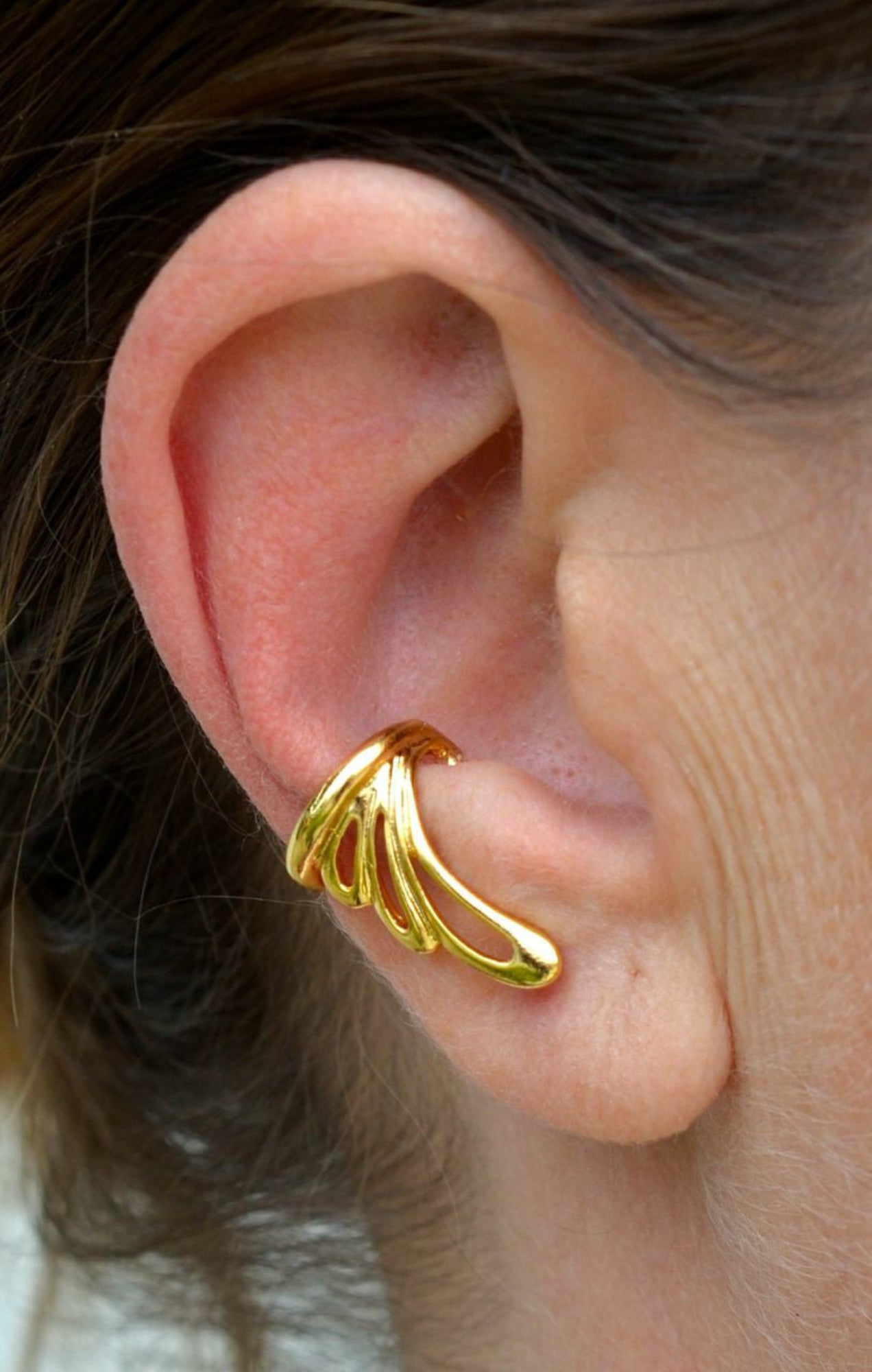 gold flowy wing ear cuff worn on ear non piercing earring side view