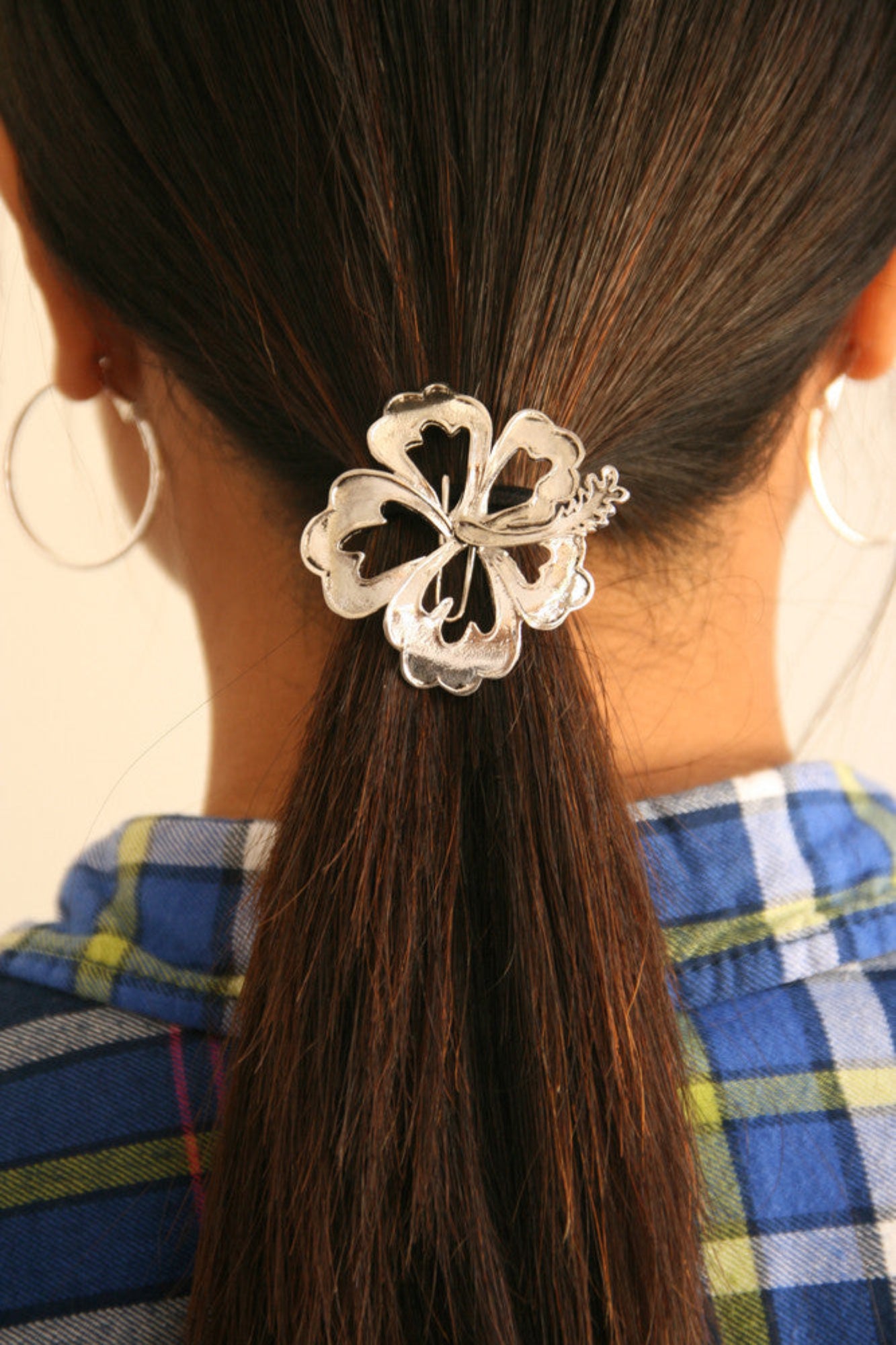 Silver hibiscus ponytail hair hook securing ponytail, back view